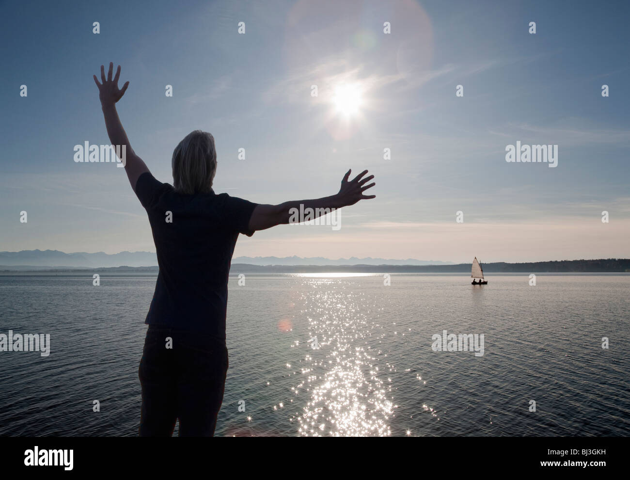 man watching the sun set over a lake Stock Photo - Alamy