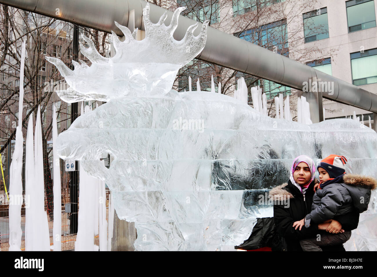 Ice sculpture of giant moose with people posing around it in Yorkville IceFest in Toronto 2010 Stock Photo