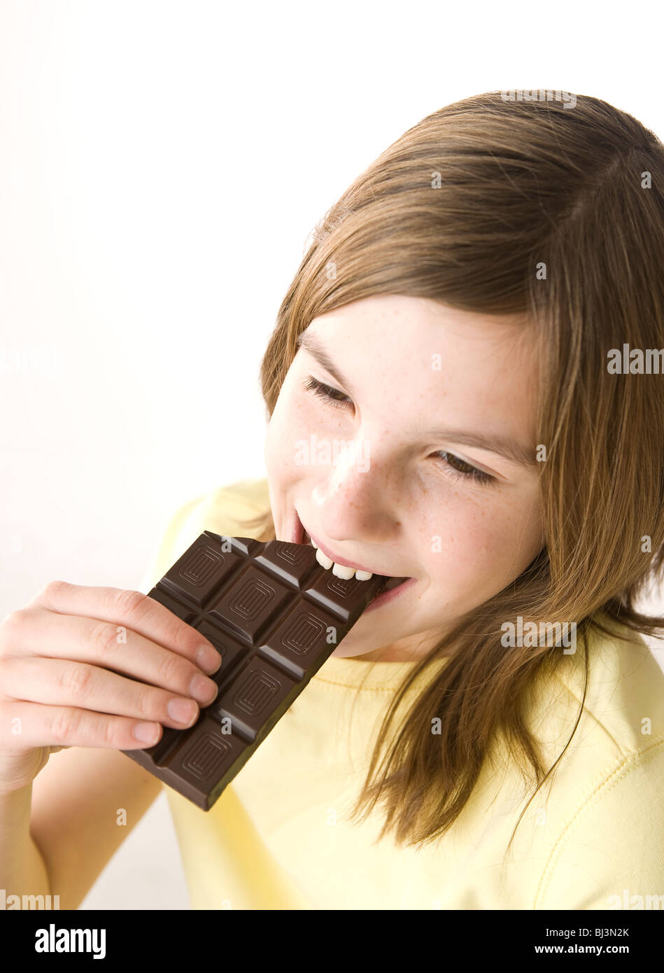 Girl biting into a chocolate bar with pleasure Stock Photo