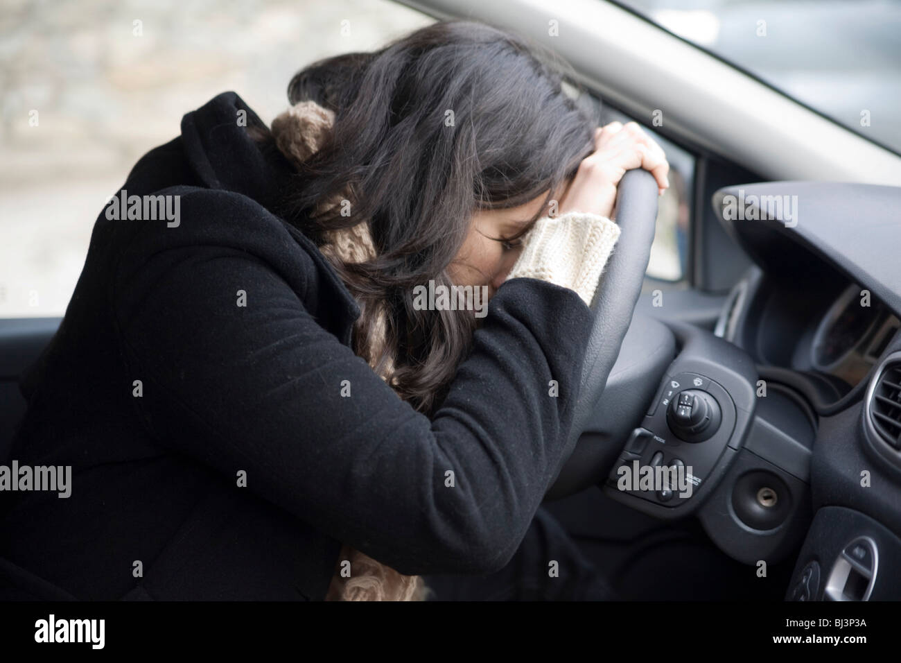 Young woman despairing at the wheel Stock Photo