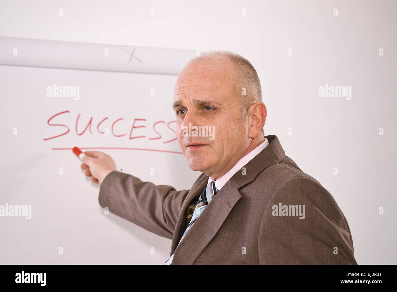 manager standing in front of a flip chart labelled success BJ3R3T