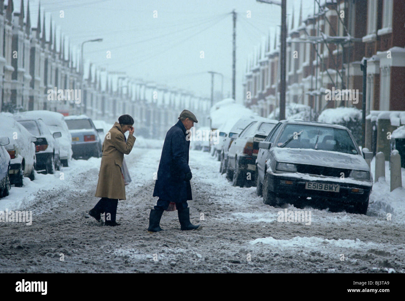 Making their way across a snow-swept road in Norwood, south London, an elderly couple tread warily as the snow turns to slush. Stock Photo
