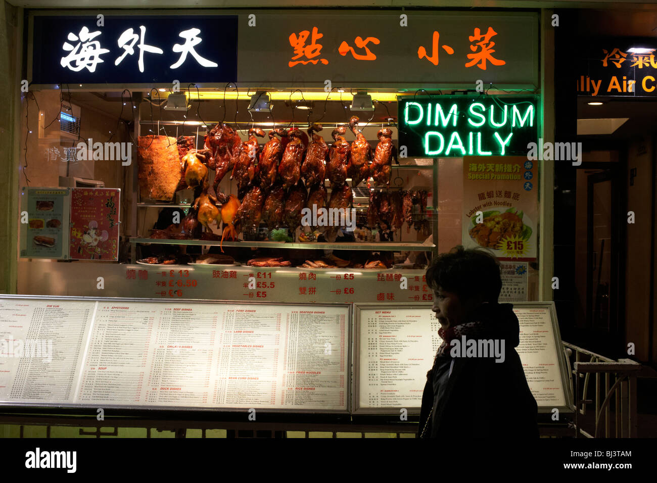 A passer-by stands next to a menu from a Chinese restaurant in Gerrard Street in London's Chinatown Stock Photo