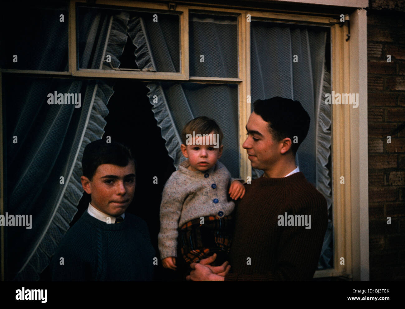 A portrait of three brothers of the same family have their picture taken outside their parents' home. Stock Photo