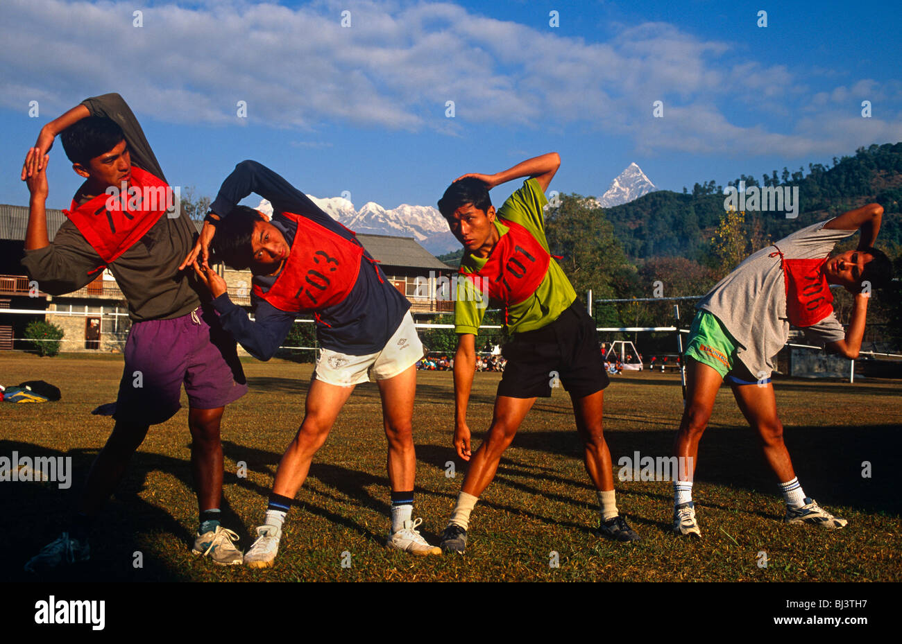 Wearing numbered bibs, four Nepali Gurkha boys warm-up before an army exercise trial known as the British Fitness Test (BFT). Stock Photo