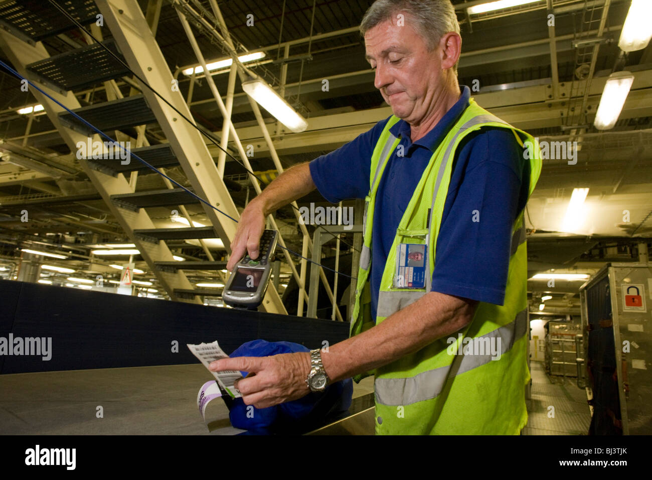 British Airways baggage handler scans the bar code of his airline passenger's item of luggage before loading it into aircraft. Stock Photo