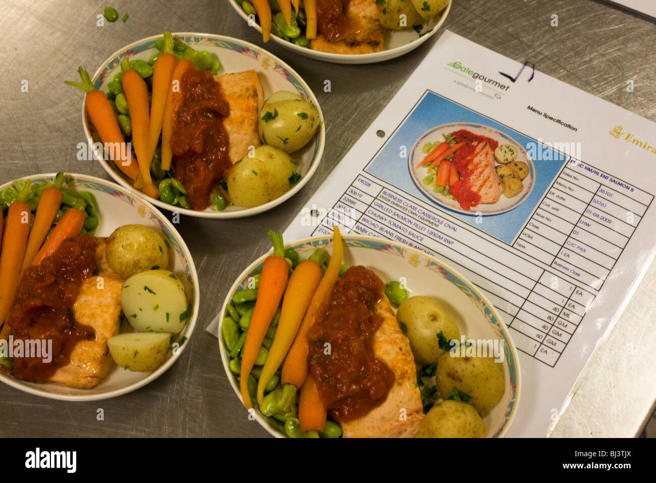 Business Class in-flight airline salmon meal are compared next to finished dishes in airline meal provider. Stock Photo