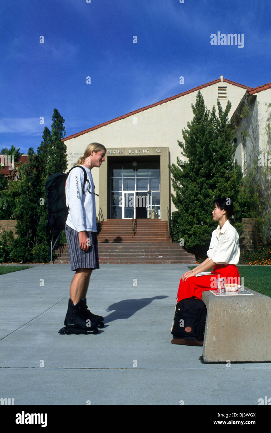 A college boy and girl talk at school. Man is wearing roller blades