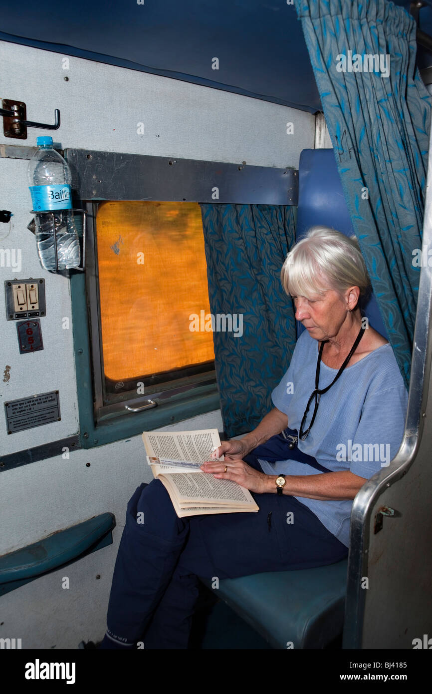 India, train travel, tourist reading book in second class two tier air conditioned (2A) compartment Stock Photo