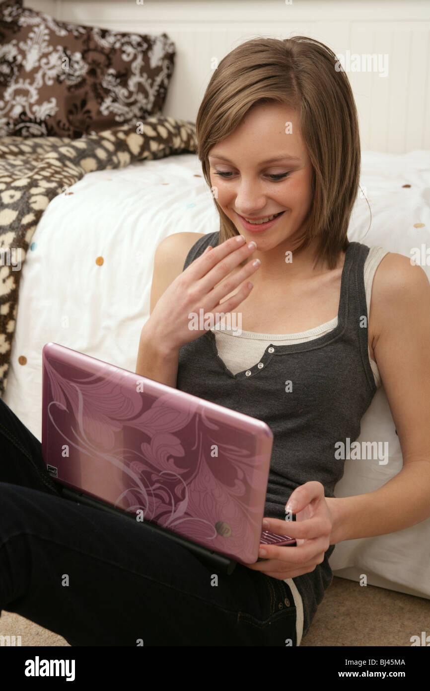 Teenage girl sitting on floor using a pink net book. Stock Photo