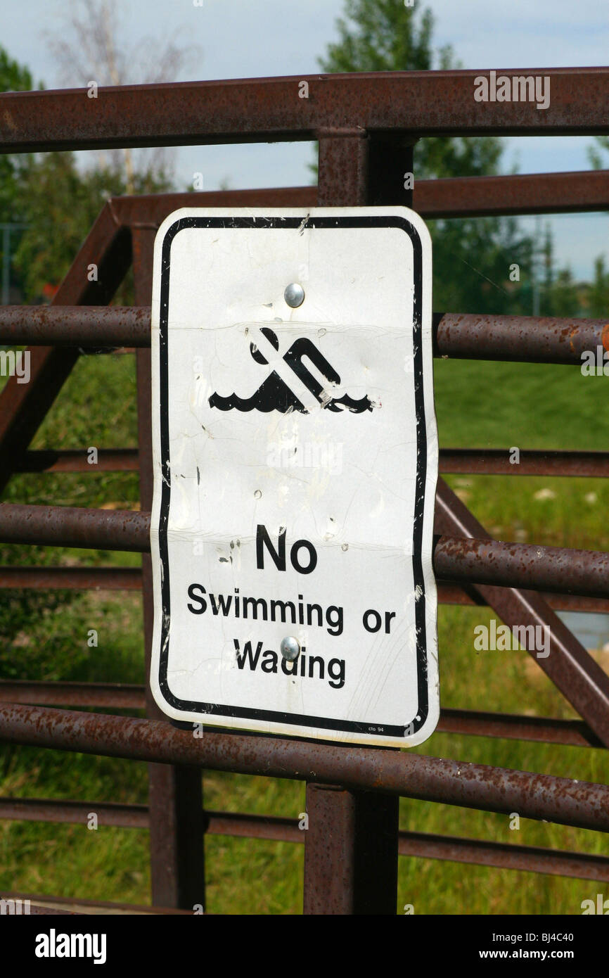 No swimming or wading sign on the rail of a foot bridge over a creek