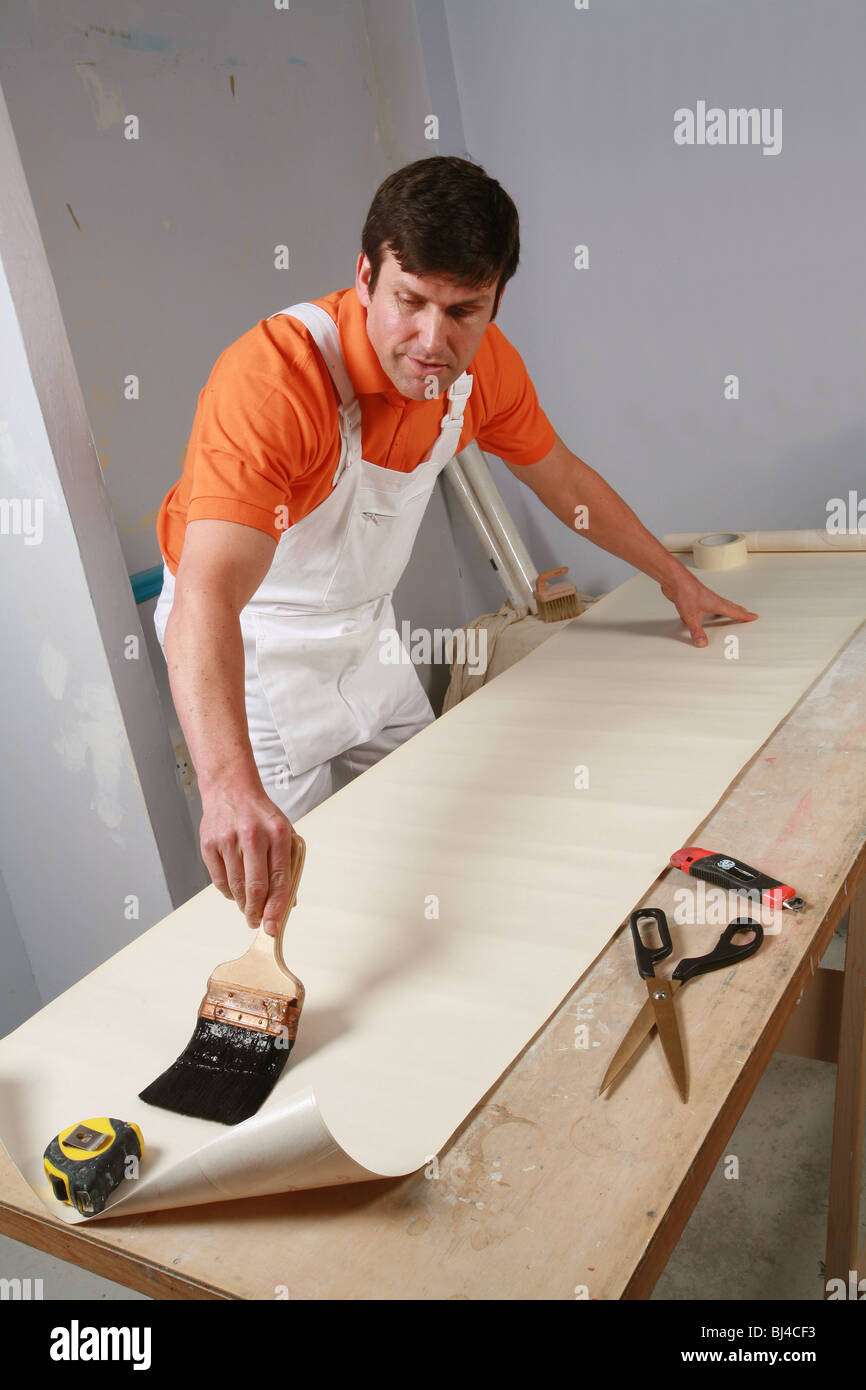 interior decorator at work wallpapering Stock Photo