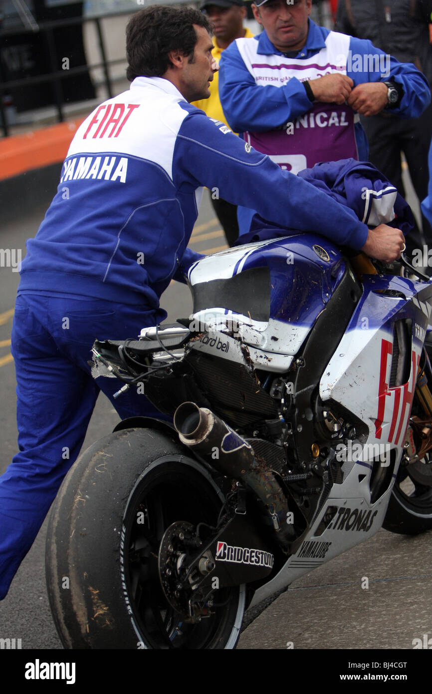 Team Fit Yamaha Mechanic pushes Jorge Lorenzo's badly damaged YZR-M1 motogp motorcycle up pit lane after he crashed at Goddards Stock Photo