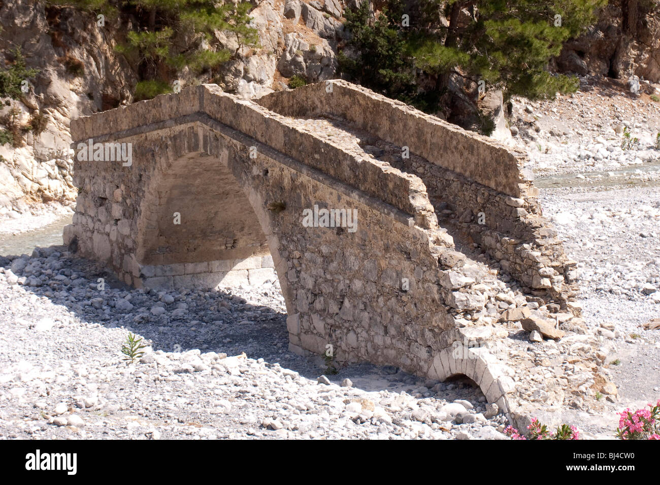An old bridge from the Roman period spans the dry river bed in the Samaria Gorge in Agia Roumeli, Crete, Greece, Europe spanned Stock Photo