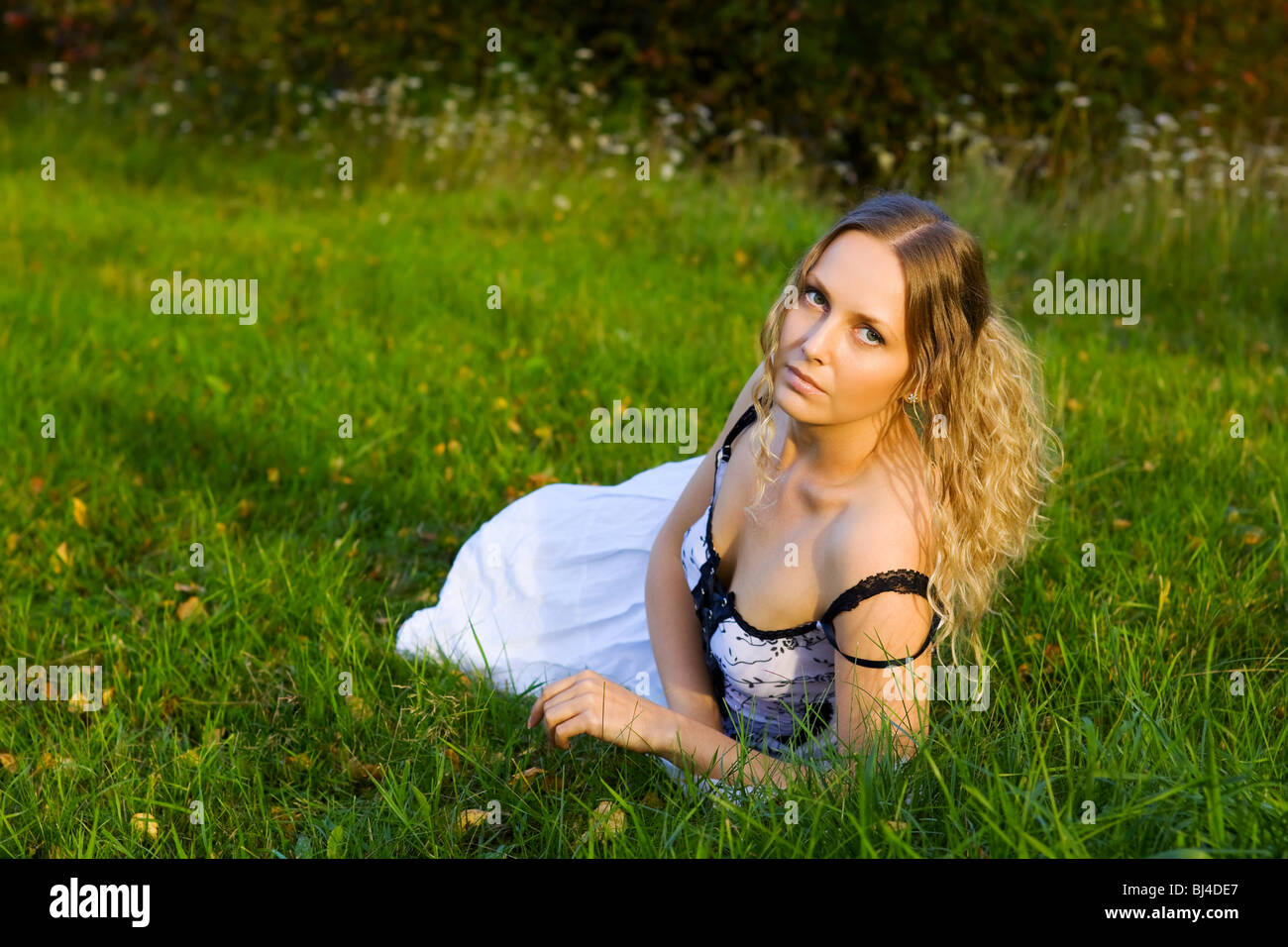 Beautiful young woman lying on the green grass Stock Photo - Alamy