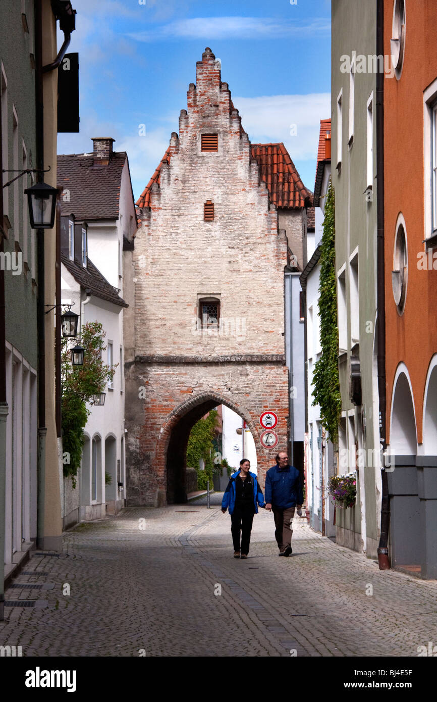 Couple walking up street with archway of Old City Gate in Landsberg am Lech, Bavaria Germany Stock Photo