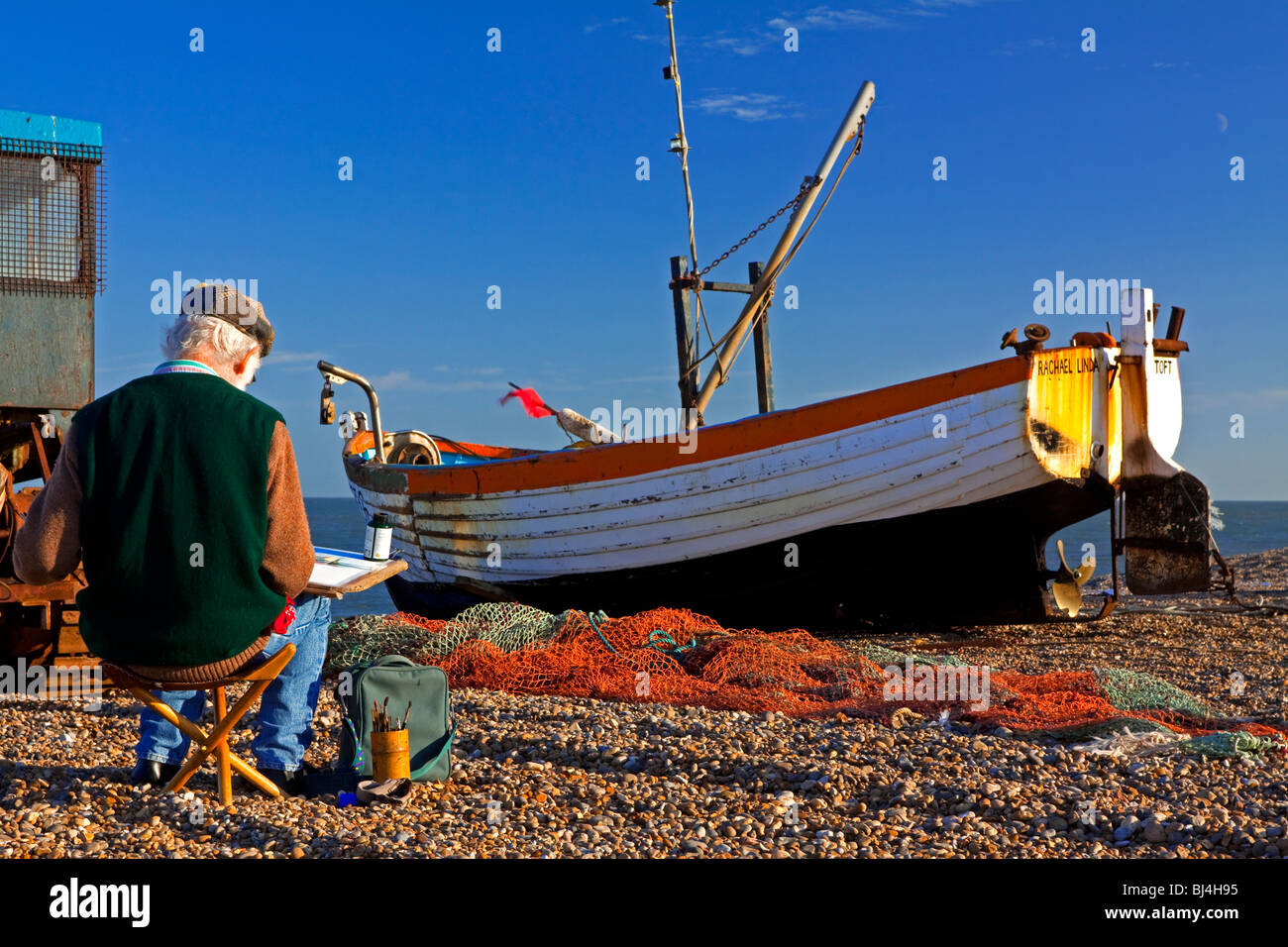 Artist painting fishing boat on the beach at Aldeburgh a fishing town in Suffolk East Anglia England UK Stock Photo
