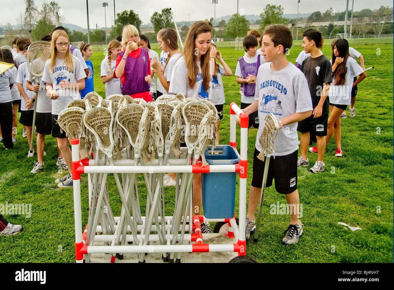 Uniformed middle school students select lacrosse sticks during physical