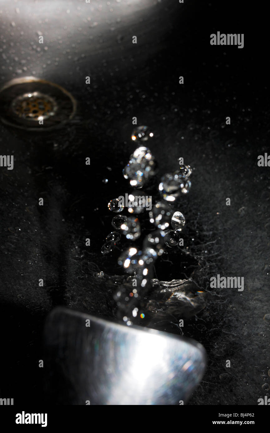 Droplets of water erupting from a drinking fountain nozzle. Stock Photo