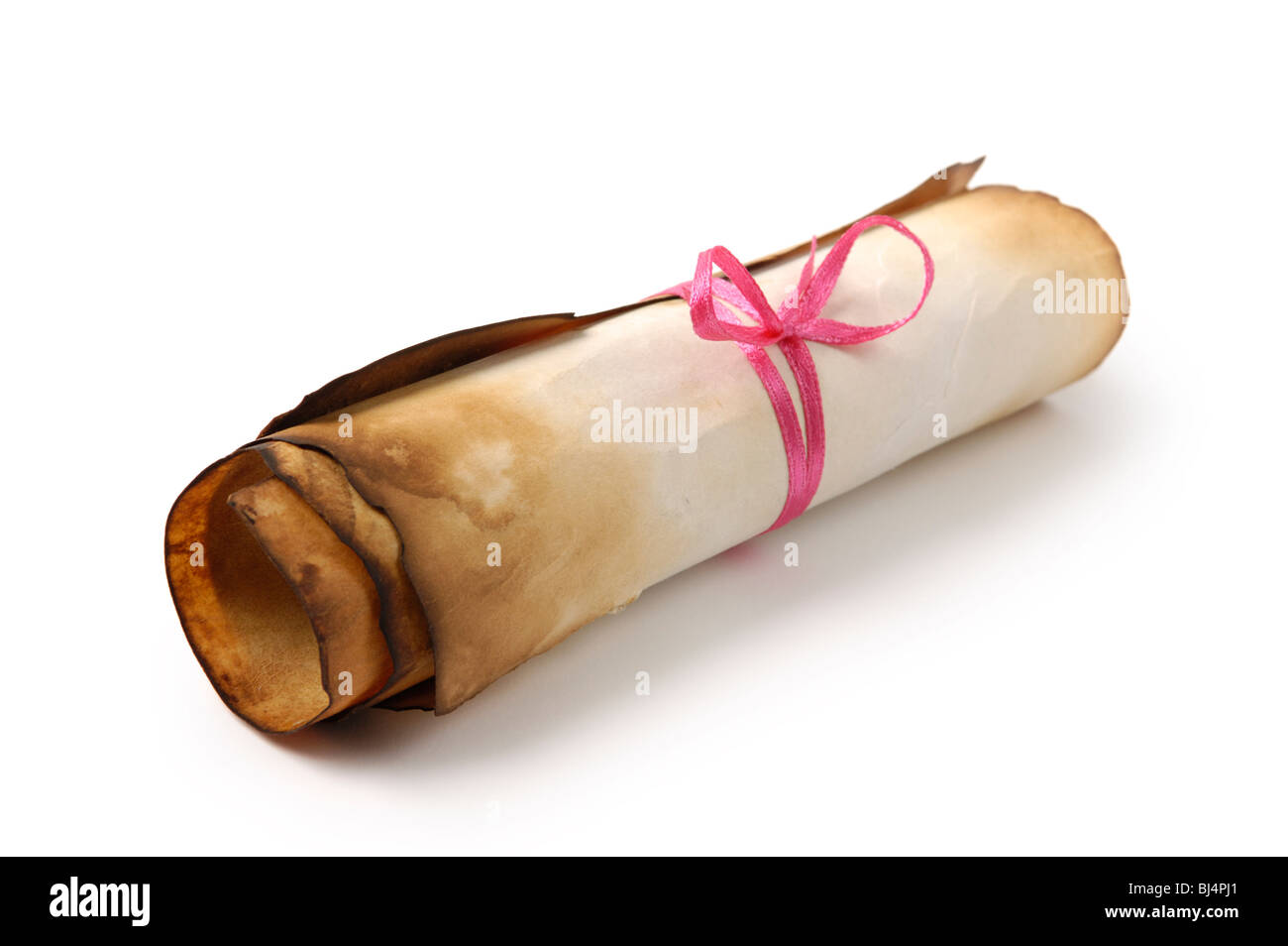 Roll of yellowish burnt vintage parchment tied with a red ribbon Isolated over white background Stock Photo