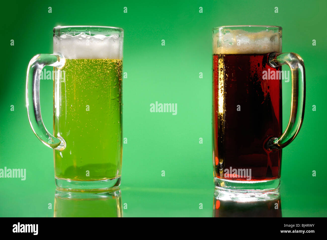 Two glasses with light and dark beer Artistic food still life over green background Stock Photo