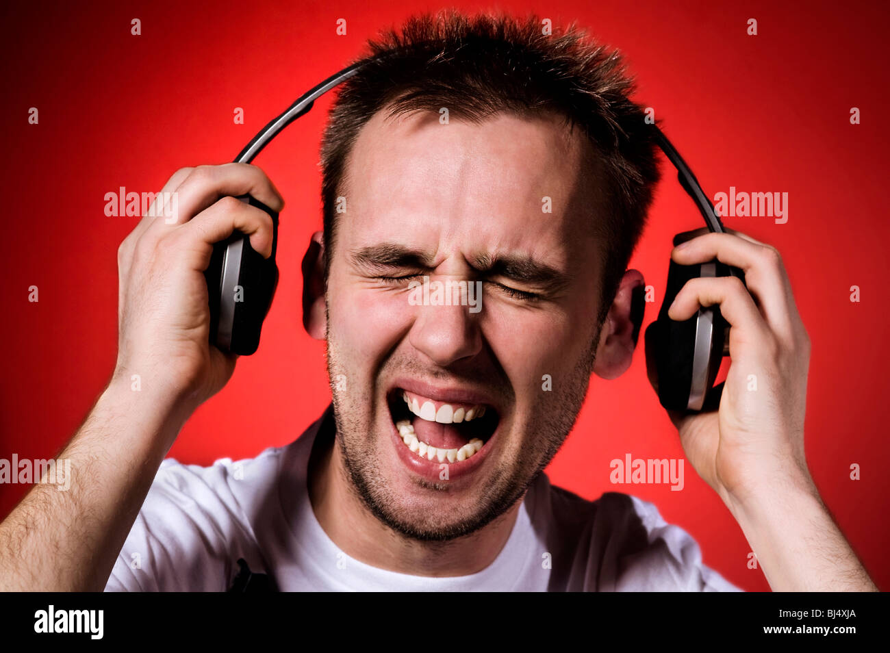 young man with wry face on his face because of loud music Stock Photo