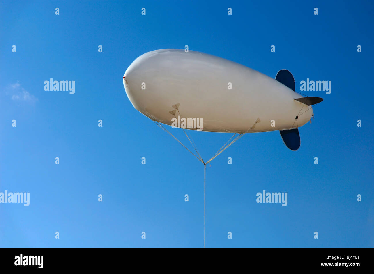 White inflatable airship hovering in blue clear sky Stock Photo