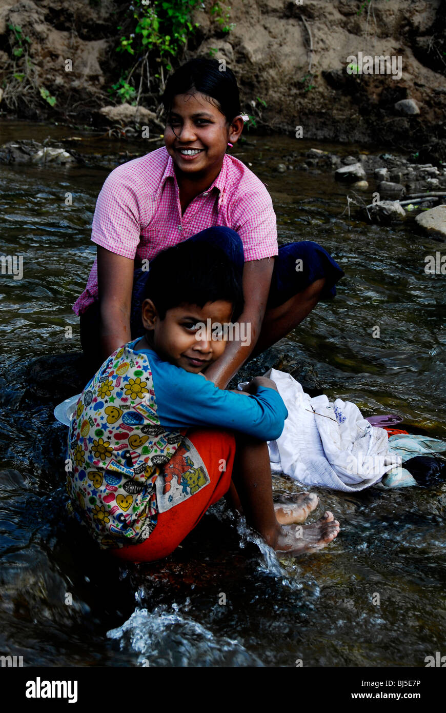 karen mother and child washing clothes in stream,mae la  refugee camp(thai burmese border) ,north of mae sot,thailand Stock Photo
