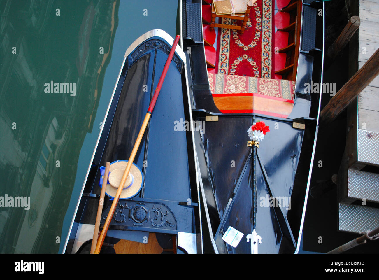 A gondolier's hat and oars lying on board his gondola in a canal in San Lio, Venice, Italy Stock Photo