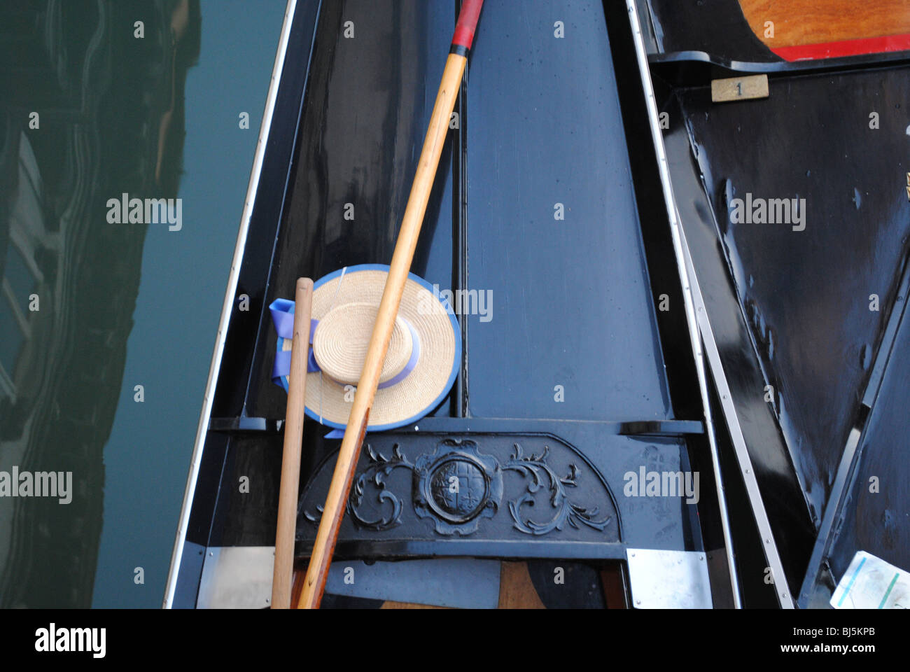 Oar and hat of a gondolier lying on board his gondola in a canal, San Lio, Venice Italy Stock Photo