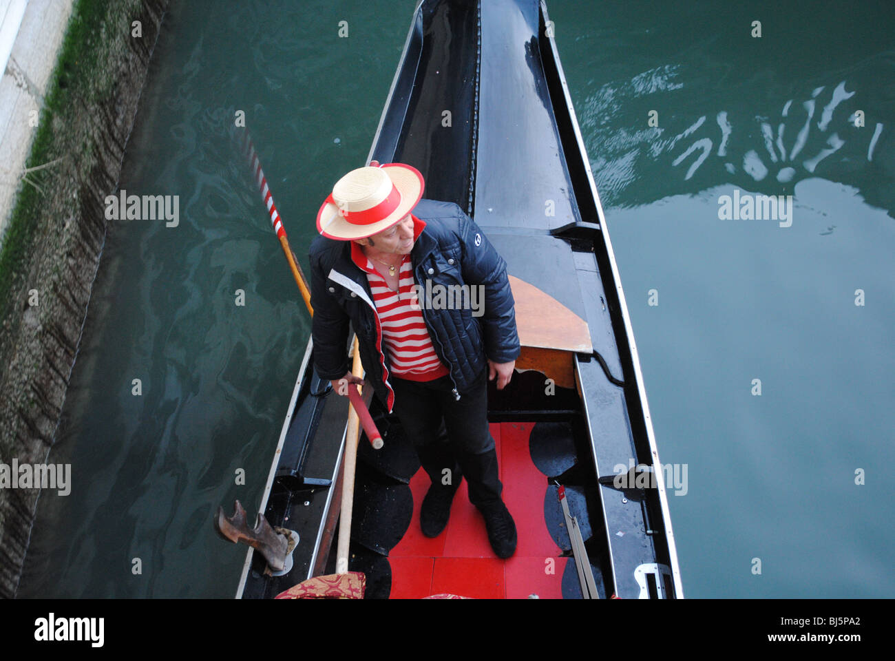 Gondolier passing under a bridge in his gondola, Venice, Italy Stock Photo
