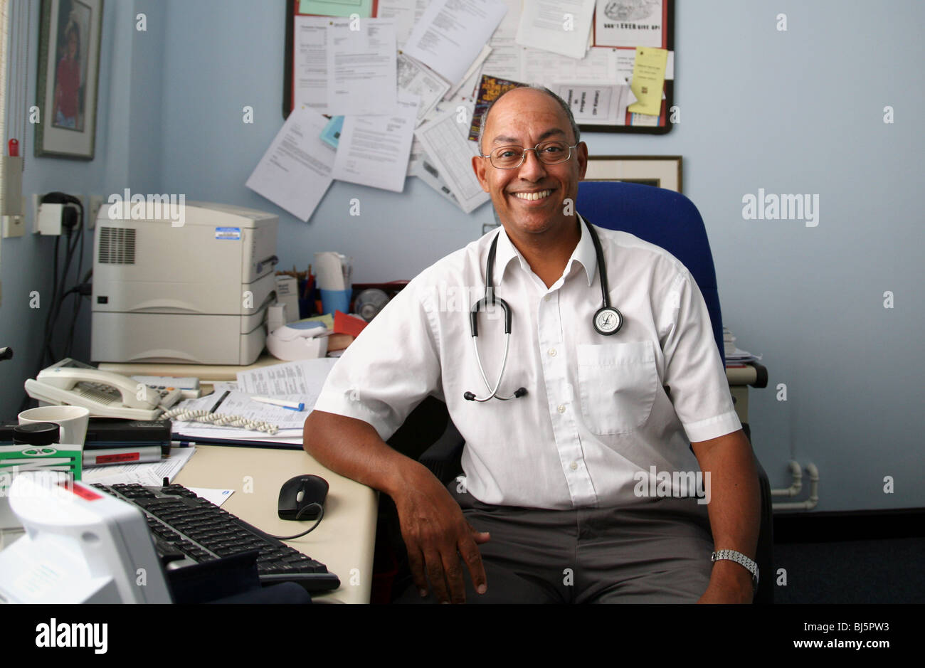 A model-released male NHS GP family doctor of asian origin in his surgery, England, UK Stock Photo