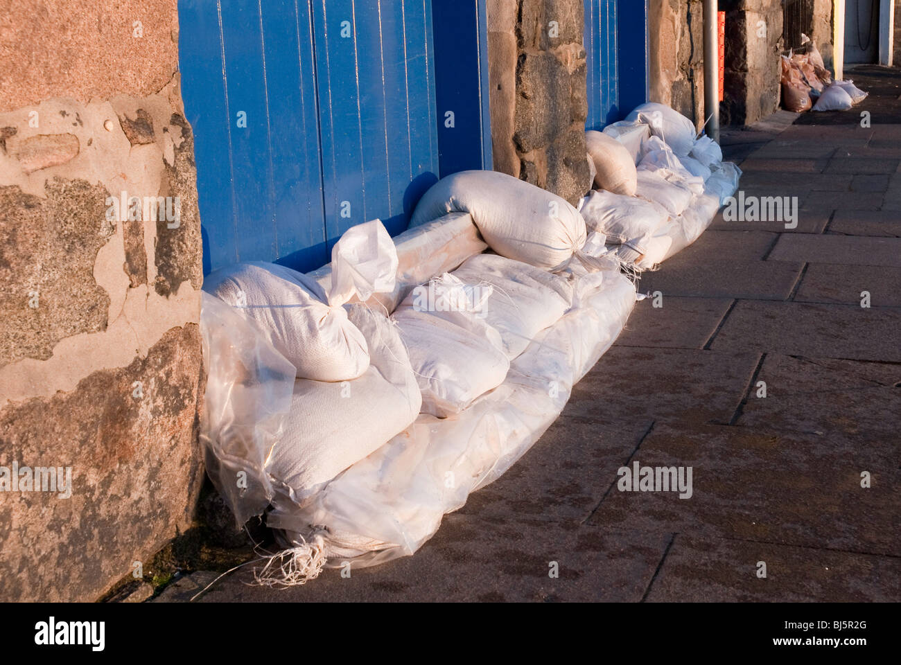 Sandbags placed against building doors in preparation for flooding due to high spring tides. Stock Photo