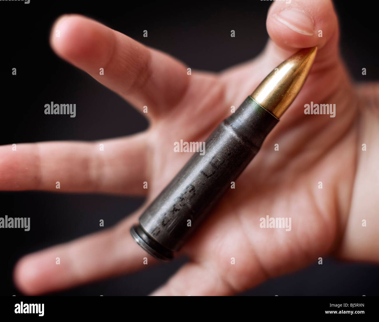 A baby holding an assault rifle cartridge Stock Photo