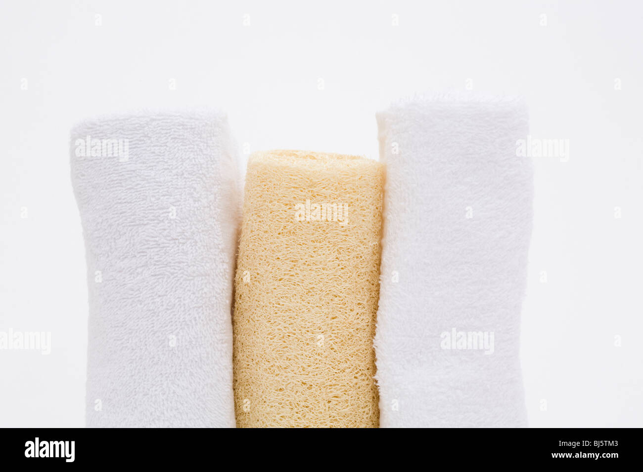 A loofah sponge between two while rolled towels Stock Photo Alamy