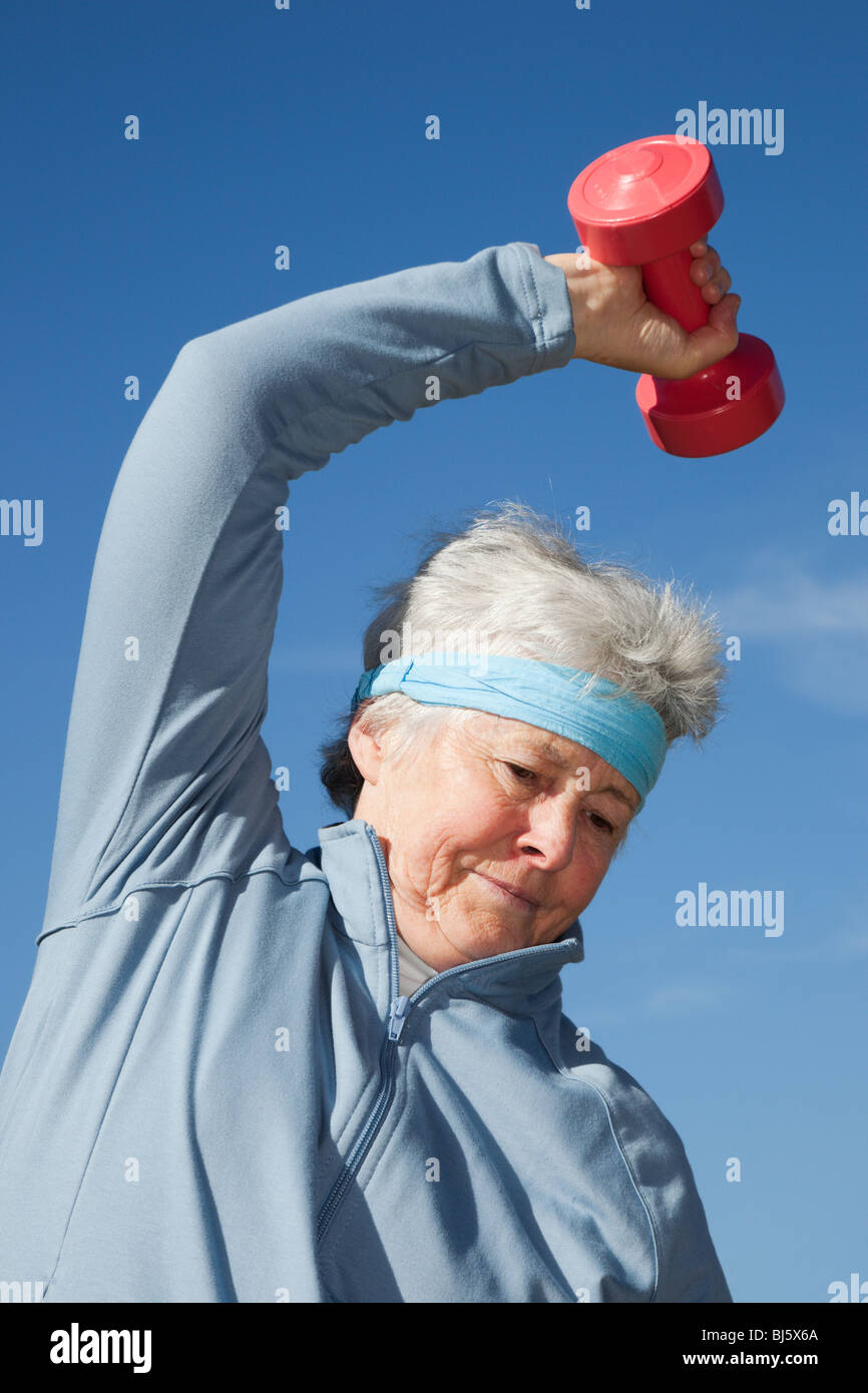 Active senior adult woman wearing a sweatband bending sideways whilst