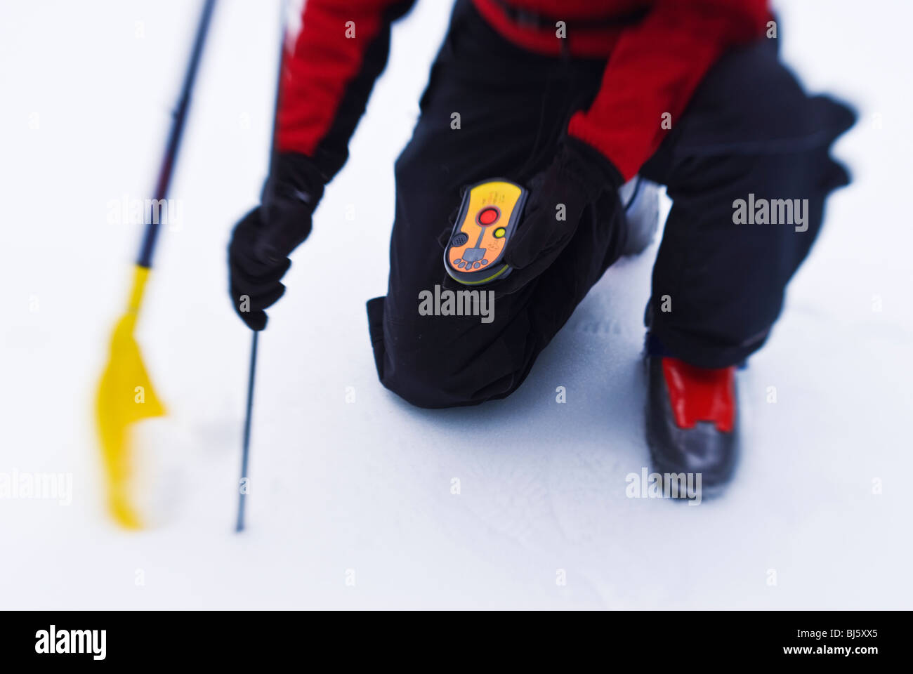 Backcountry skier using an avalanche beacon, probe and shovel to locate
