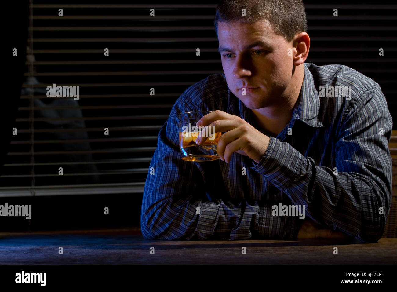 Man sitting at the office/home with a glass of whiskey Stock Photo