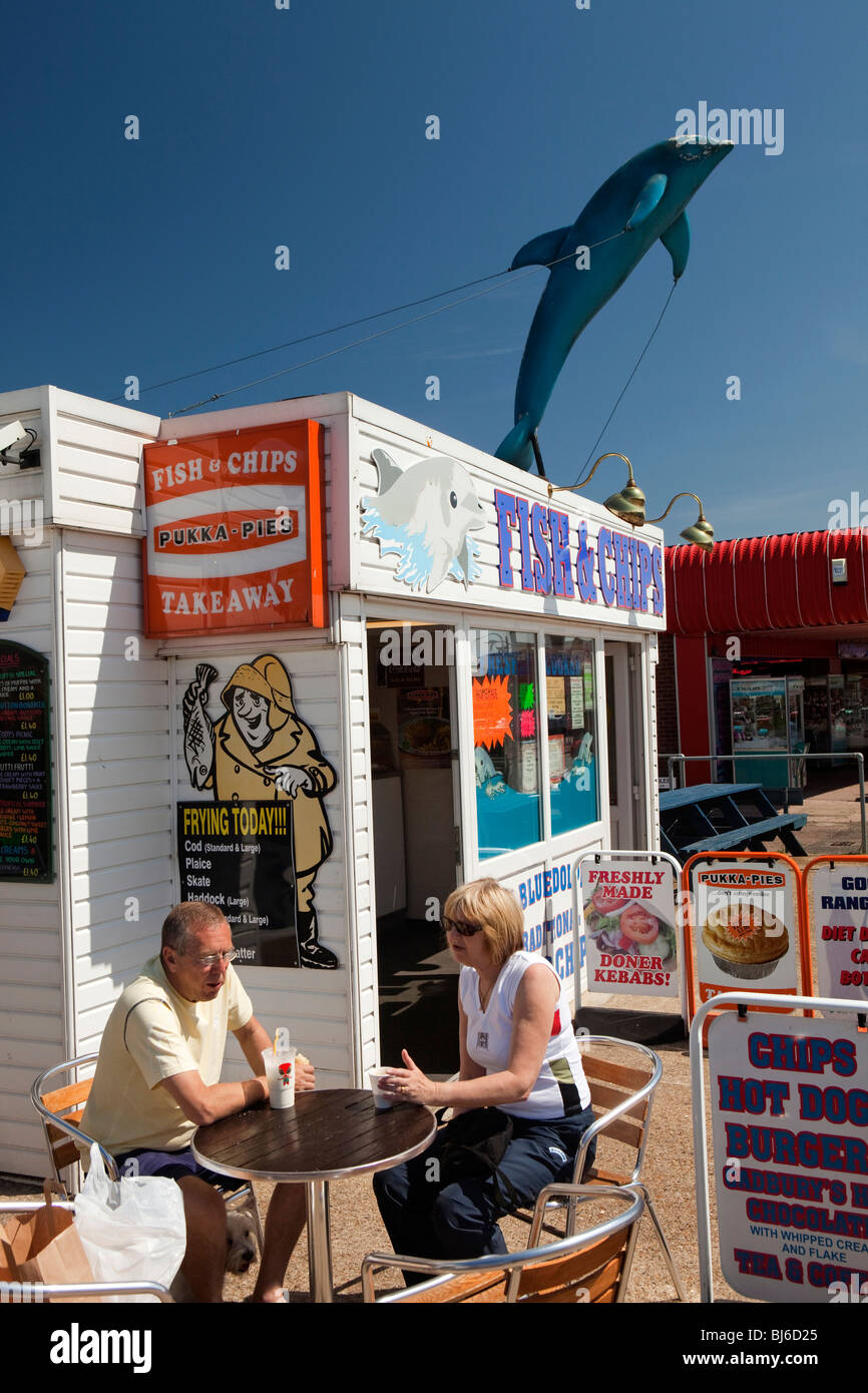 UK, England, Norfolk, Hemsby, Beach Road, couple at fish and chips takeaway stall sitting in sunshine Stock Photo