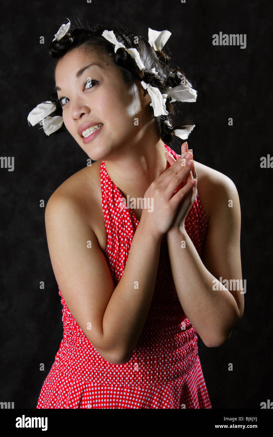 Happy Smiling Chinese Girl Wearing a White Spotted Red Dress with Paper Ties in Her Hair. Stock Photo