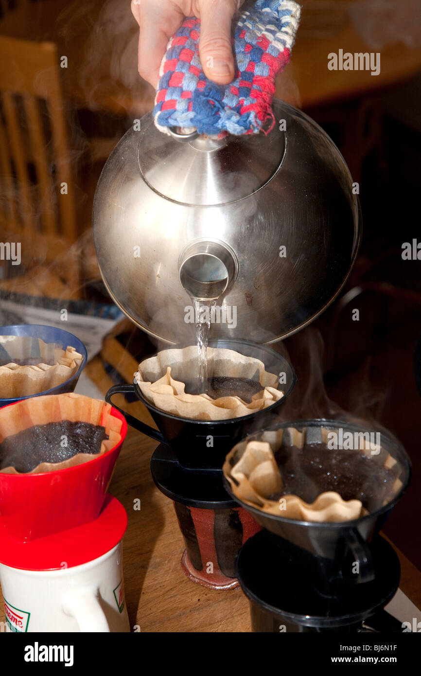 Making brewing filtered coffee by pouring hot water over coffee grounds
