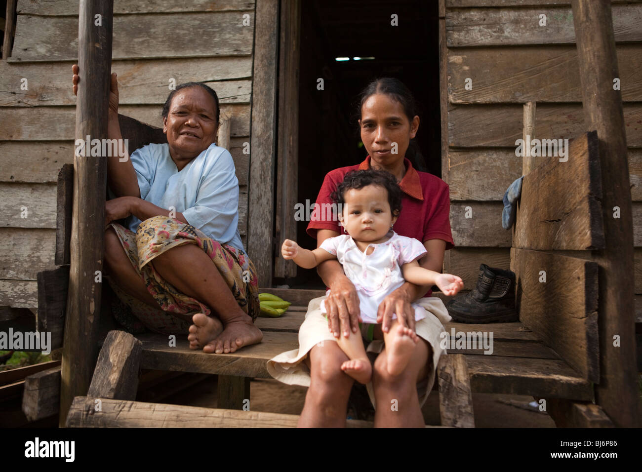 Indonesia, Sulawesi, Buton, Labundo Bundo, three generations sitting on step of house Stock Photo