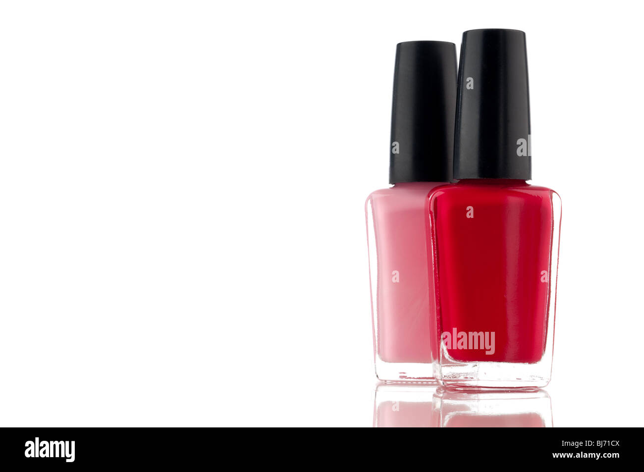 Horizontal image of red and pink nail polish on a white reflective surface Stock Photo