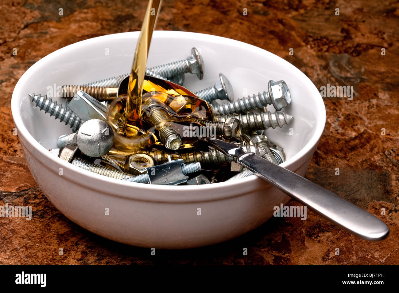 Horizontal image of oil being poured onto a breakfast serving of nuts and bolts Stock Photo