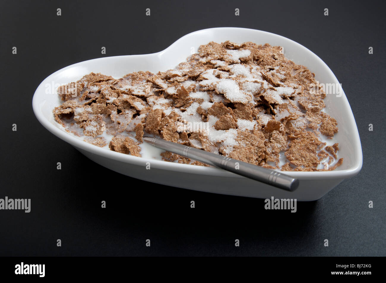 Heart-shaped cereal bowl or dish, with spoon and cereals on black