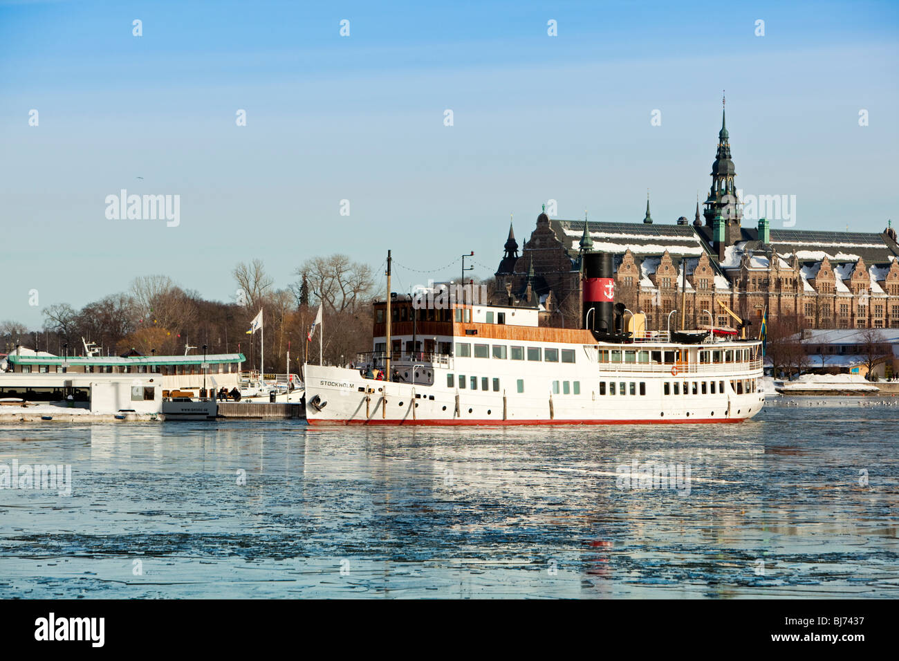 Steamship arrives at Nybroviken with frozen water in foreground and Nordic museum in background Stock Photo