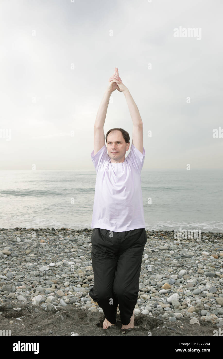 Man doing yoga on beach Stock Photo