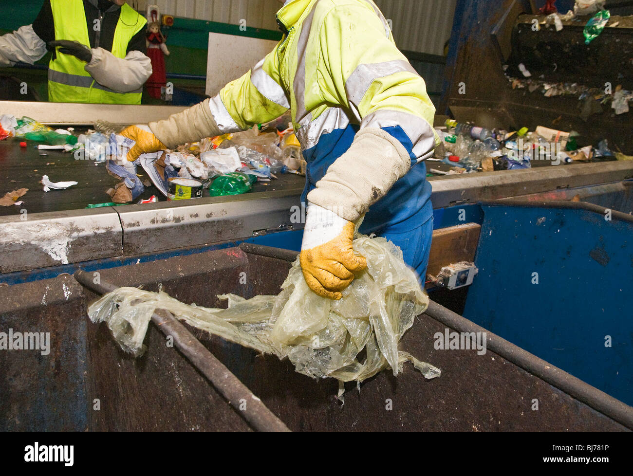Recyclable waste sorting center. Employees on each side of the conveyor belt manually sort the different types of waste according to their recycling. Stock Photo
