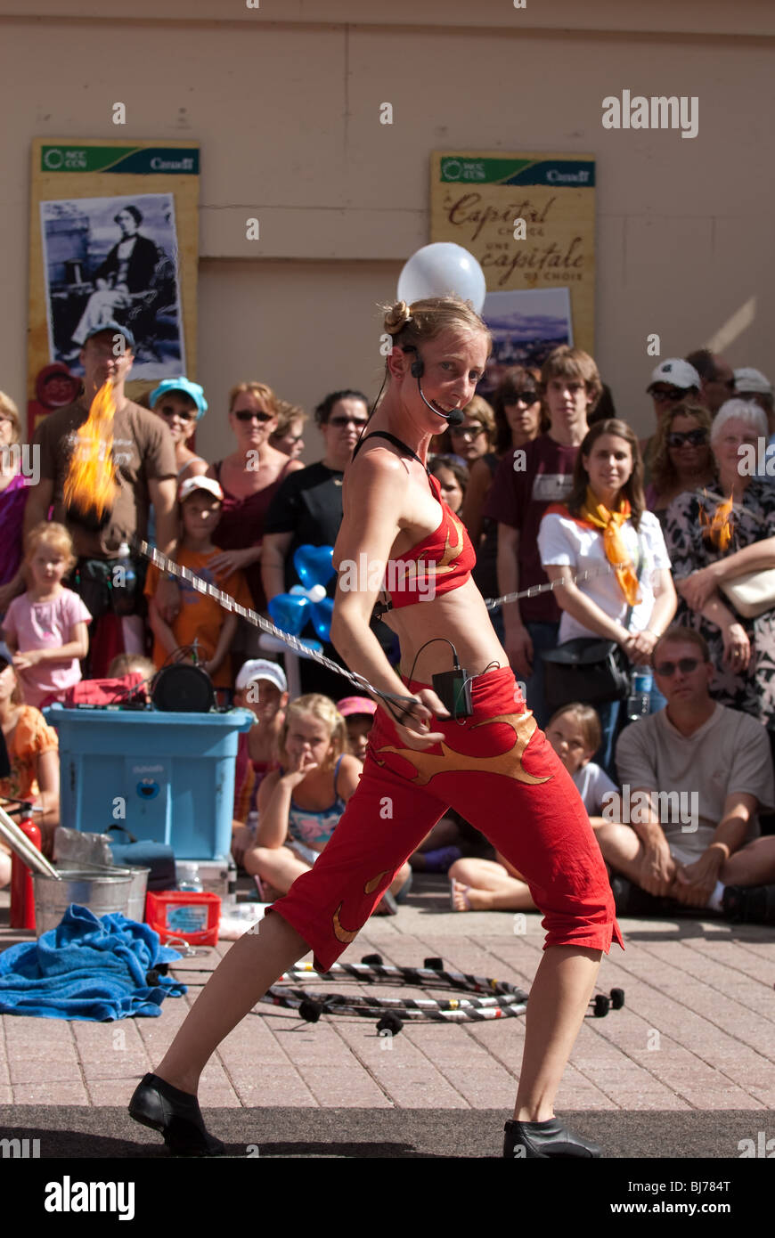 A female busker performs tricks with spinning balls of flame at Ottawa's Annual Busker Festival. Stock Photo