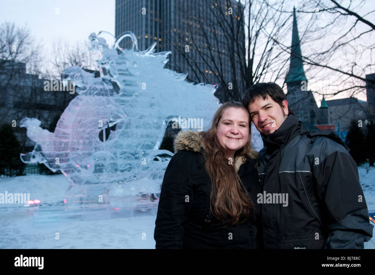 A young smiling couple pose in front of an ice sculpture during annual Winterlude festivities in Ottawa, Canada. Stock Photo
